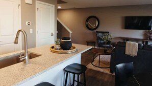 A modern kitchen with a granite countertop, stainless steel faucet, and a small island with stools.