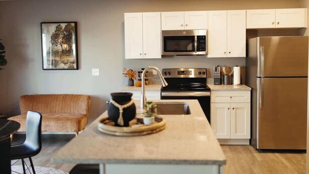 A modern kitchen with white cabinets, stainless steel appliances, and a central island.