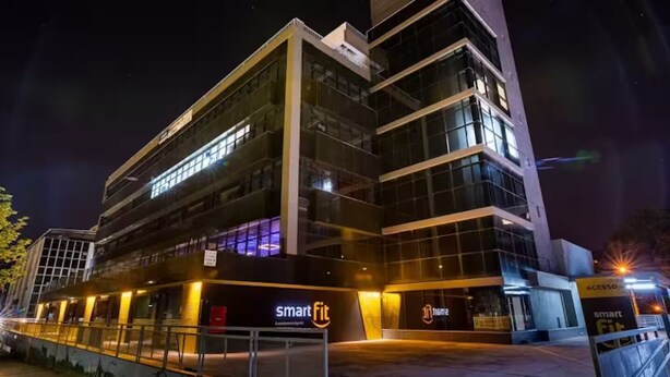 En moderne bygning med en glasfacade, mærket "Smart Fit", og et skilt med "Acesso".