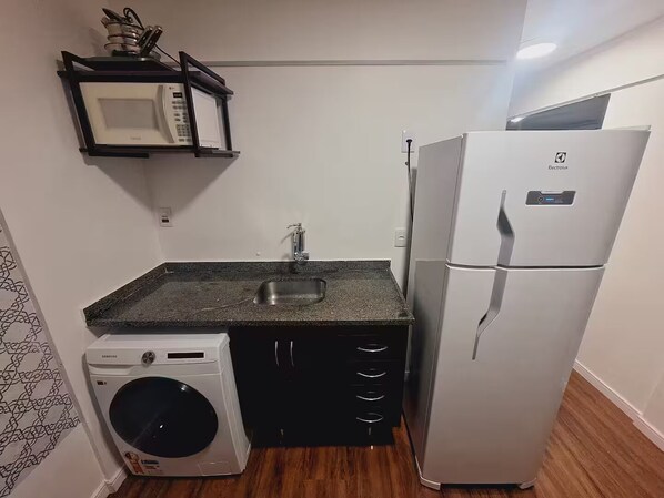 Cocina compacta equipada con microondas, fregadero, lavadora y refrigerador.