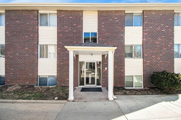 A multi-story building with a central entrance featuring a covered porch. - Poppleton Place - Central Omaha, Zoo, CHI Nearby (Omaha)