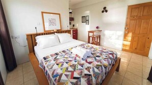 A neatly arranged bedroom with a bed, a small desk, and a door. - Irie Heights Oceanview (Gros Islet)