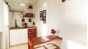 A compact kitchen with a wooden table and two stools, a small island with a sink, and a wall-mounted light fixture. - Irie Heights Oceanview (Gros Islet)