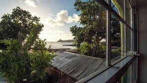 A view from a window overlooking a beach with trees and a clear sky. - Irie Heights Oceanview (Gros Islet)