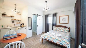 Ein kleines Zimmer mit einem Bett, einem Tisch und einer Küchenzeile.