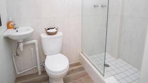 Ein Badezimmer mit Toilette, Waschbecken und einer Duschkabine aus Glas.