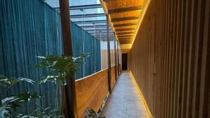 Un couloir avec un plafond en bois, un mur en verre et un plancher en bois.