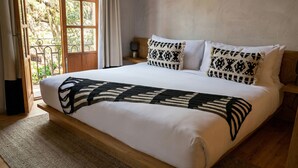 Un lit avec un couvre-lit à motifs, des oreillers blancs et une tête de lit en bois.