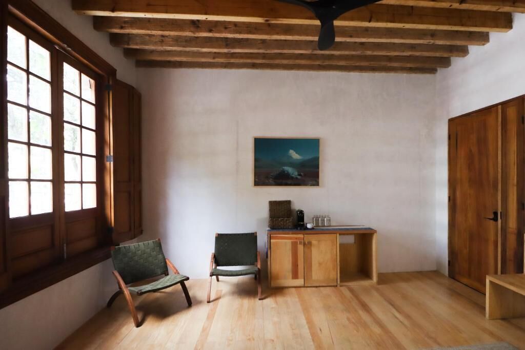 A room with wooden flooring, a wooden bench, a cabinet, and a painting on the wall.