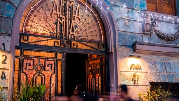 Un bâtiment doté d’une grande entrée en arc de cercle, d’une enseigne indiquant « casa » et d’une autre enseigne indiquant « ALMINA ».