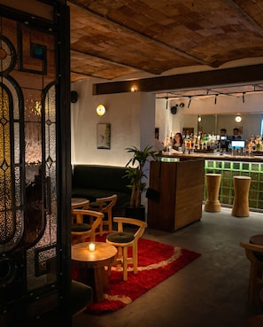 A bar area with wooden furniture, a red rug, and a bar counter with bottles.