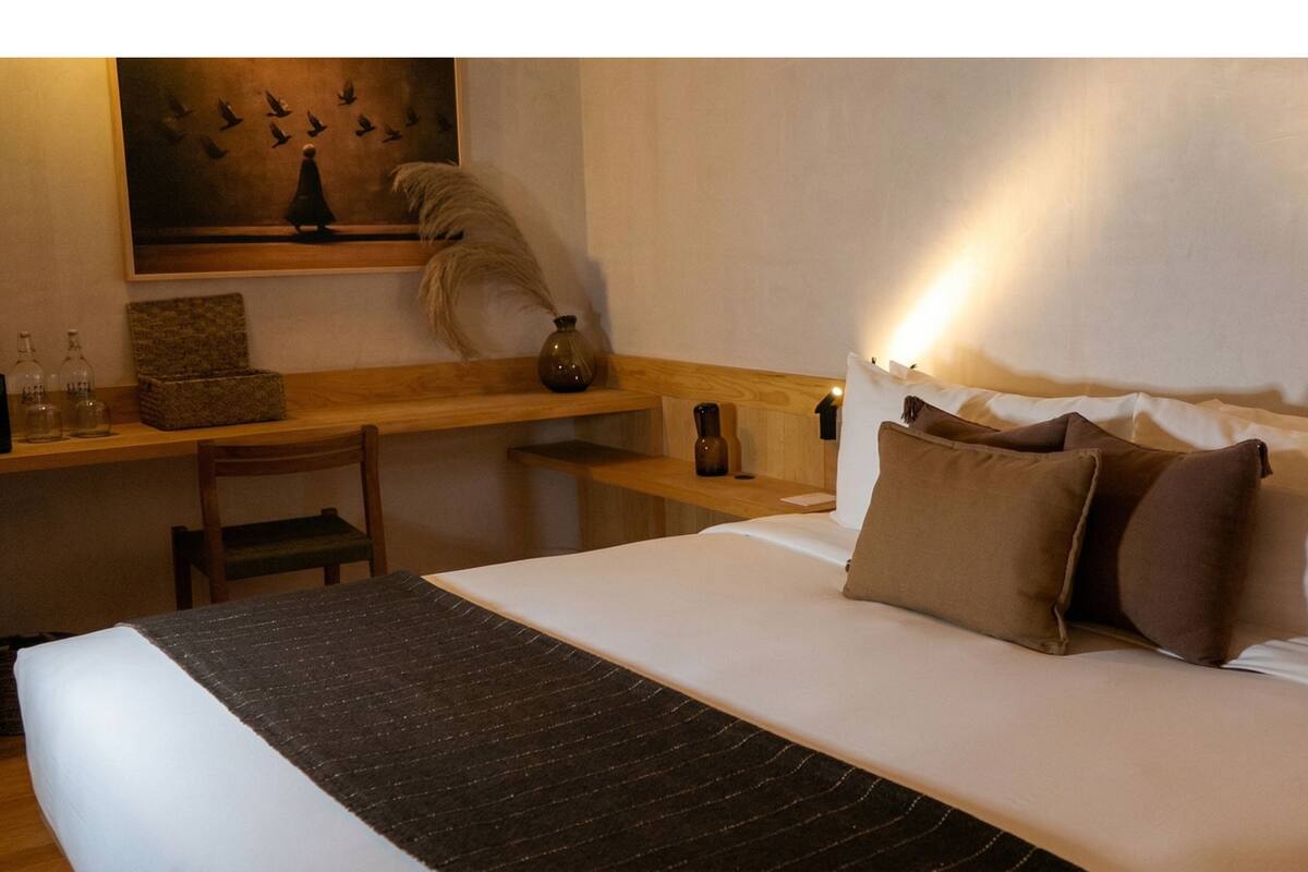 Een hotelkamer met een bed, een bureau, een stoel, een schilderij en een vaas.