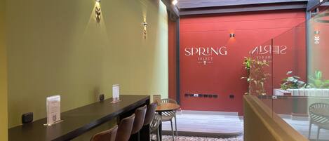 A reception area with a counter, chairs, and a red wall with the text "SPRING SELECT EST. 2025".