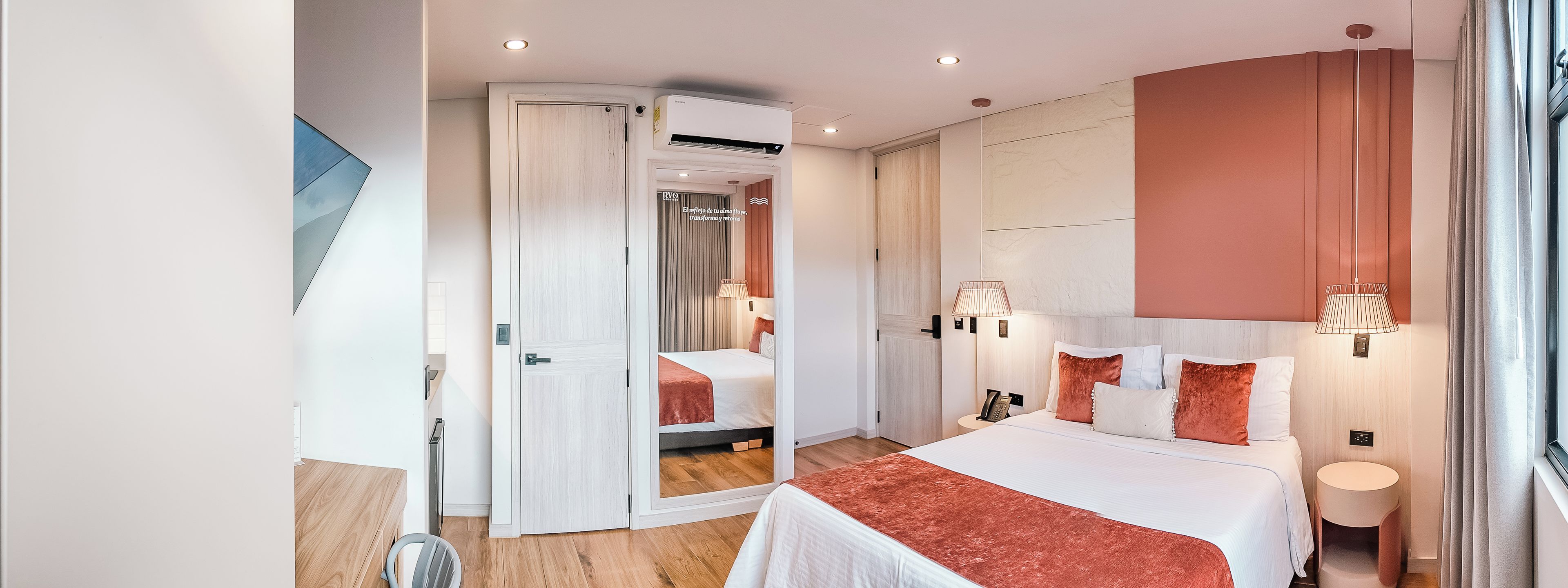 Habitación de hotel con cama, lámparas de noche, teléfono y vista al exterior.