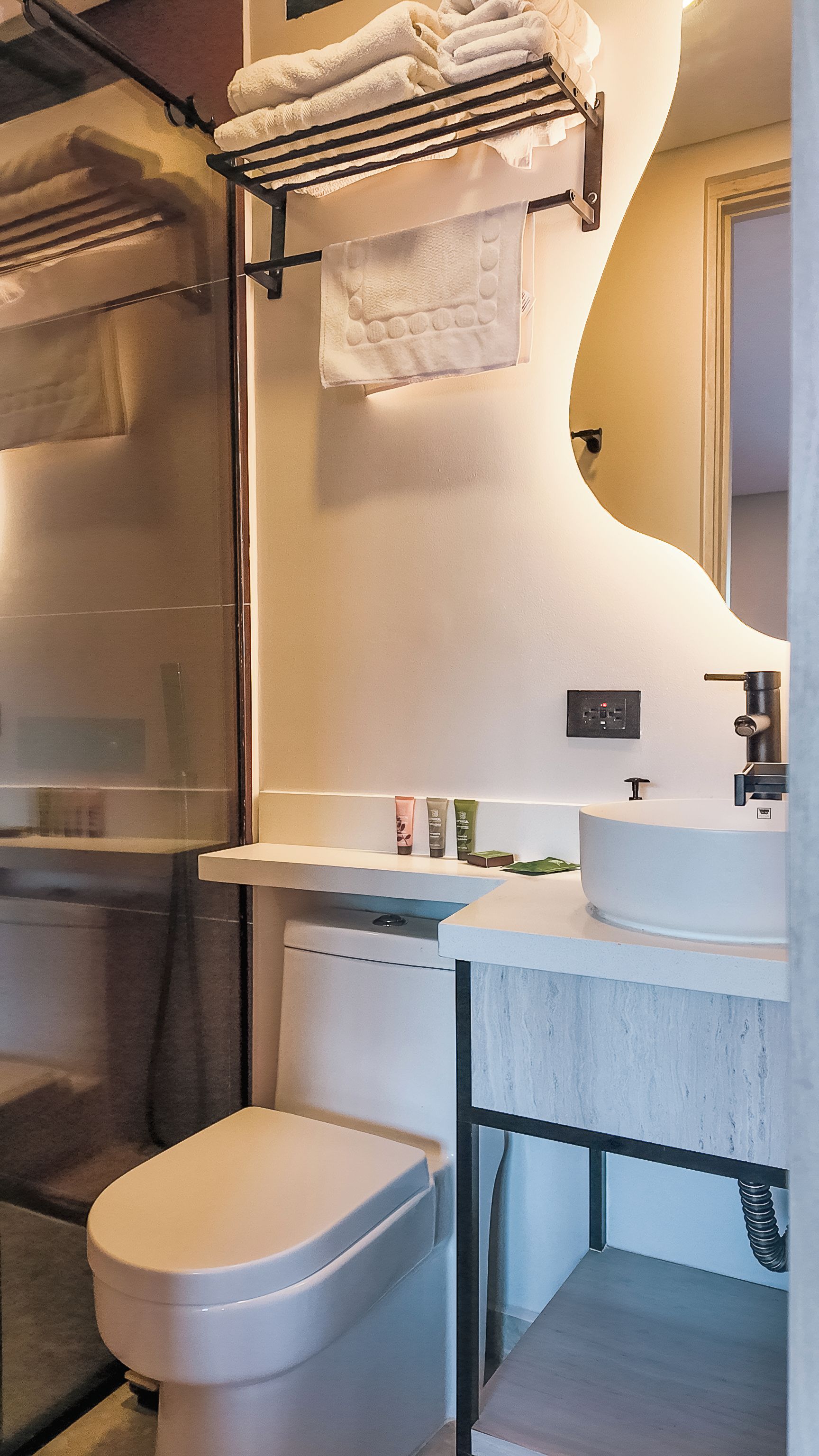 Un baño con inodoro blanco, lavamanos y zona de ducha.
