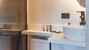 Un baño con inodoro blanco, lavamanos y zona de ducha.