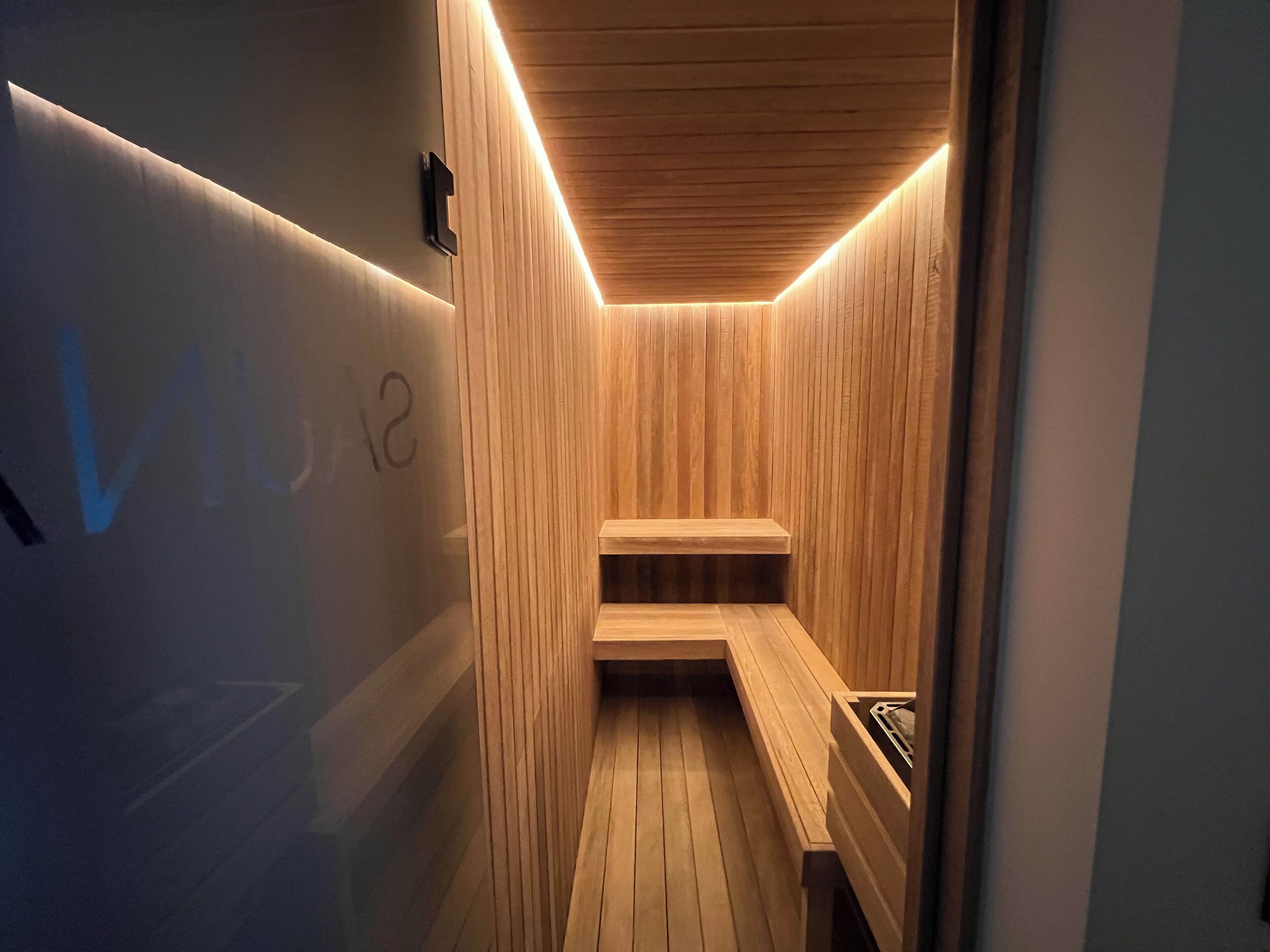 A sauna with wooden walls and benches, a wooden floor, and a ceiling with a wooden panel design.