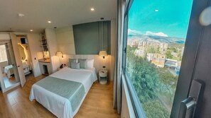 A modern hotel room with a large bed, bedside lamps, a view of the city, and a balcony. - Hotel Ryo 74B Suites by Growing Group (Medellín)