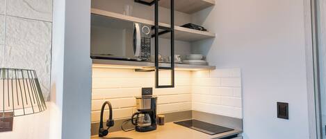 Una cocina moderna con microondas integrado, cafetera y pileta de acero inoxidable.