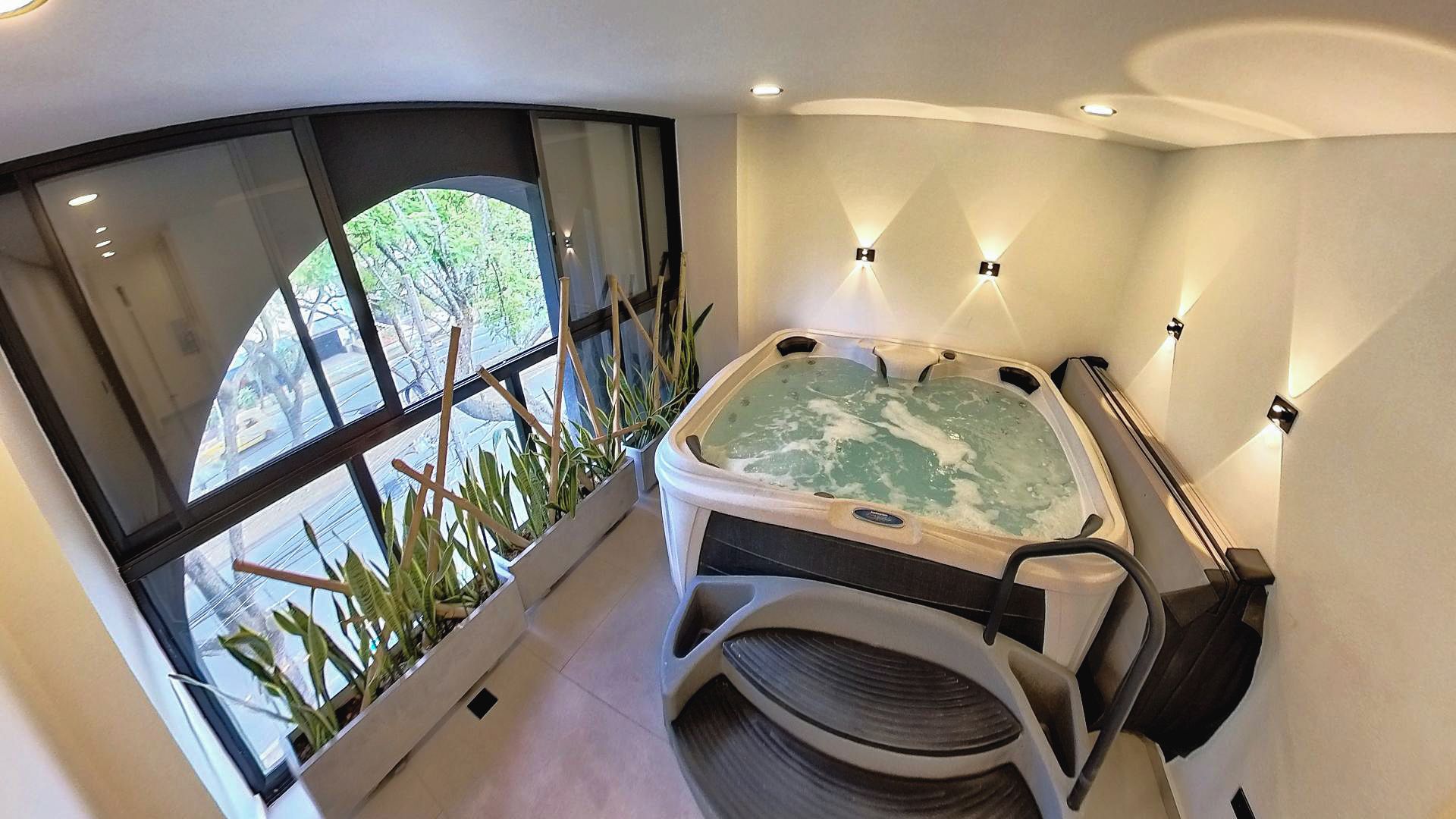 Casa de banho moderna com banheira de hidromassagem, janelas amplas e vista para o verde.