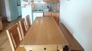 A kitchen with wooden cabinets, a microwave, a sink, and a dining table with chairs.