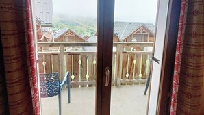 A balcony with a wooden railing and a view of houses in the background.