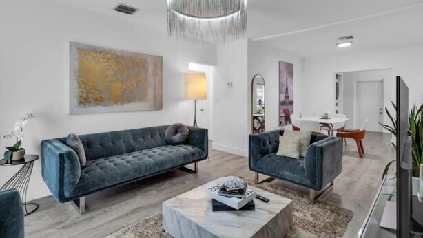 Un salon moderne avec un grand canapé, un canapé plus petit, une table basse et un luminaire suspendu.