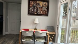 Een eetgedeelte met een tafel, stoelen, een kunstwerk aan de muur en een raam met uitzicht.