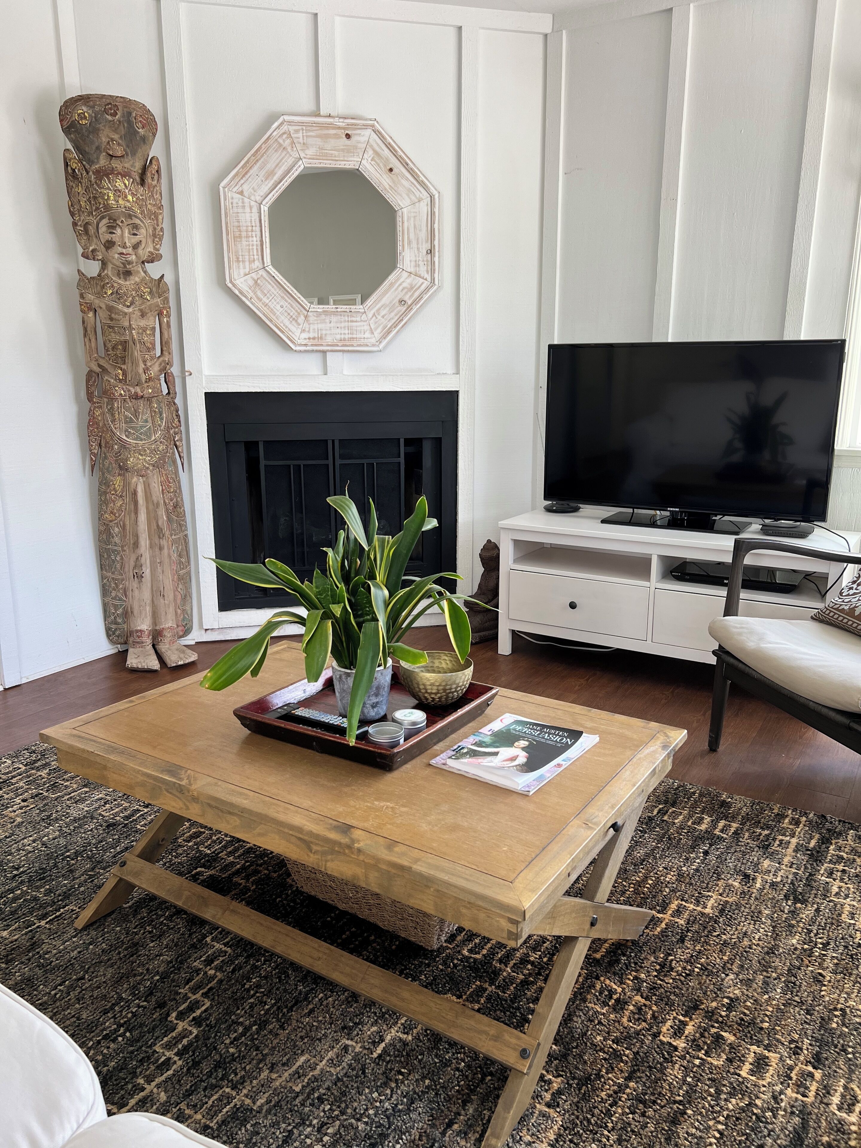 A living room with a wooden coffee table, a fireplace, a television, and a large decorative sculpture.