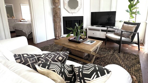 A living room with a white sofa, a coffee table with decorative items, a TV, and a fireplace.