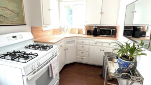 A kitchen with white cabinets, a stove, a microwave, and a sink.