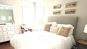 A bedroom with a large bed, a dresser, a mirror, and a ceiling fan.