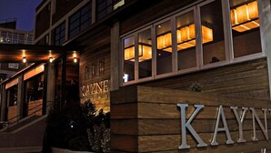 A hotel entrance with a wooden facade and illuminated windows. - Pool, Rooftop Deck, City View, Gym + Gated Garage (Nashville)