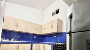 A kitchen with light wooden cabinets, a black oven, and a stainless steel refrigerator.