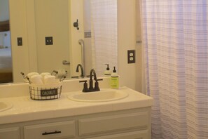 A bathroom with a white sink, a mirror, and a towel rack with a "Organize" sign.