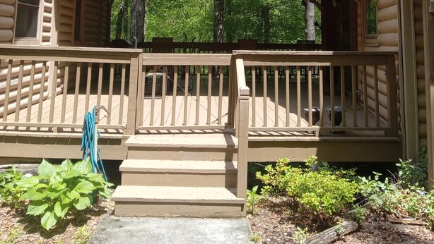 A two-story log cabin with a balcony and a covered porch.