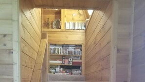 A wooden staircase leading to a loft bedroom with a bookshelf and a ceiling fan.