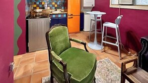 A room with a green armchair, a small table, a white chair, and a tiled backsplash. - Cozy Casita 1bd/1bth 3 min to Farmer's Market (Las Cruces)