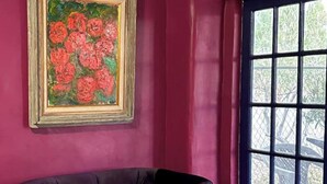 A room with a large window, a framed painting of flowers, and a dark-colored sofa. - Cozy Casita 1bd/1bth 3 min to Farmer's Market (Las Cruces)