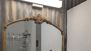 A mirror with an ornate gold frame in a room with a wooden wall and a white door.