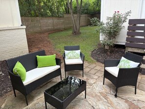 An outdoor patio with a black wicker sofa, two chairs, and a glass coffee table. - Modern Beauty in Crestline Park (Birmingham)