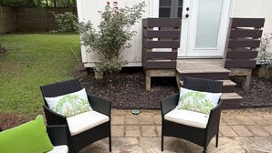 A patio with two wicker chairs with cushions, a small table, and a wooden bench. - Modern Beauty in Crestline Park (Birmingham)