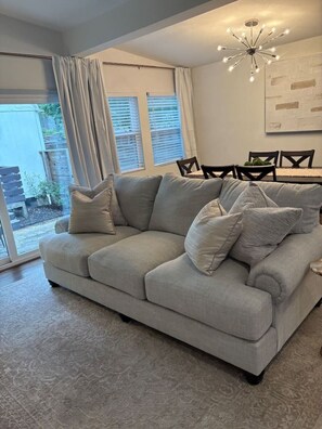 A living room with a sofa, a dining table with chairs, and a chandelier. - Modern Beauty in Crestline Park (Birmingham)
