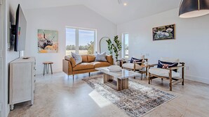A spacious living room with a large window, a ceiling fan, and a modern coffee table.