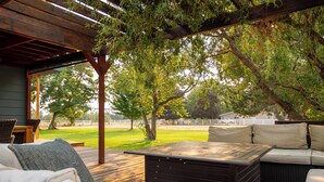 Ein überdachter Außenbereich mit Holzterrasse, einer Couch mit Kissen und einem Tisch.