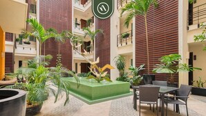 Un atrium à plusieurs niveaux, doté d’un grand jardinier central, d’un espace extérieur aménagé pour s’asseoir et d’une variété de plantes.