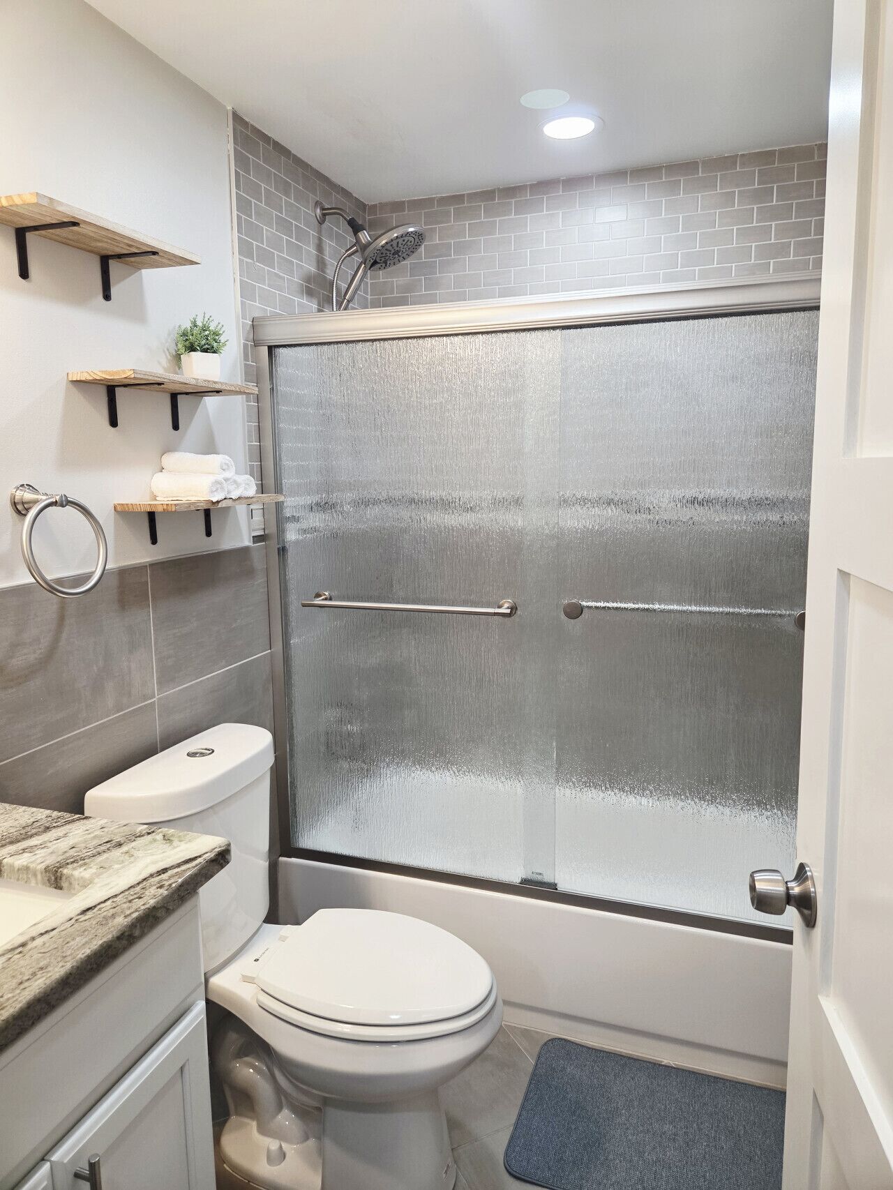 Een moderne badkamer met douchecabine, toilet en wastafel met een marmeren blad.