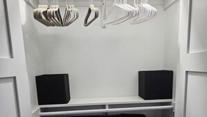 A walk-in closet with white shelving, a black storage unit, and hanging clothes racks. - Charlie`s by the Bay #3 (New Baltimore)