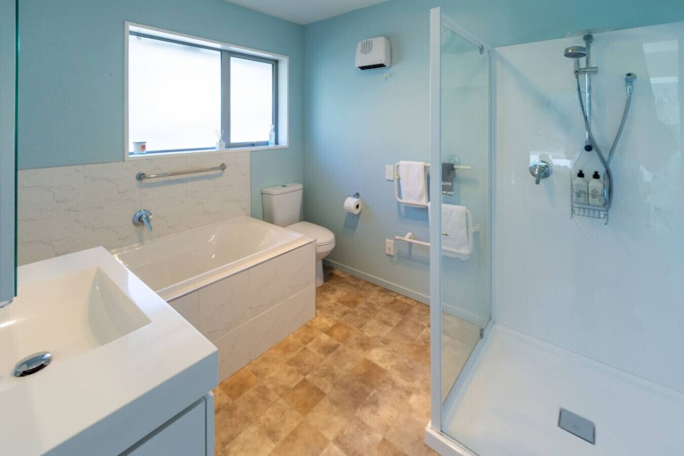 A bathroom with a bathtub, toilet, and glass-enclosed shower.