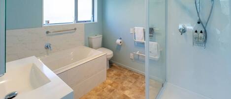 A bathroom with a bathtub, toilet, and glass-enclosed shower.